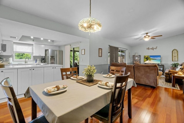 dining space with light wood-style floors, plenty of natural light, ceiling fan with notable chandelier, and visible vents