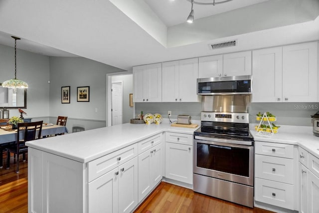 kitchen with white cabinets, appliances with stainless steel finishes, light wood-style floors, a peninsula, and visible vents