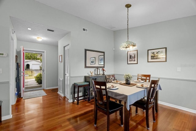 dining room with baseboards, visible vents, and wood finished floors