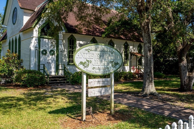 community / neighborhood sign with a lawn, an attached garage, and driveway