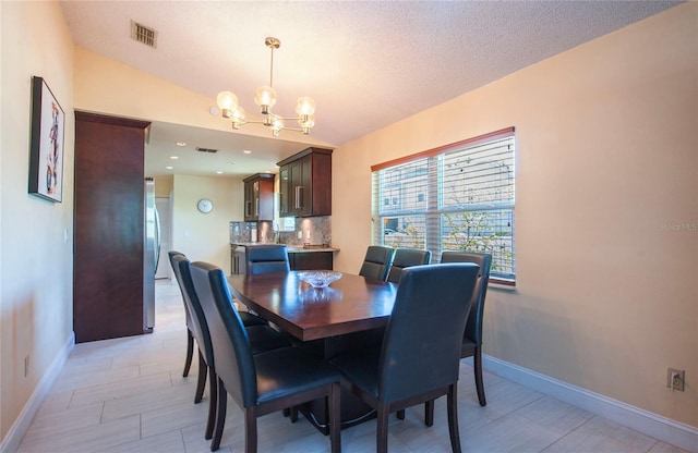 dining area with baseboards, visible vents, a notable chandelier, and a textured ceiling