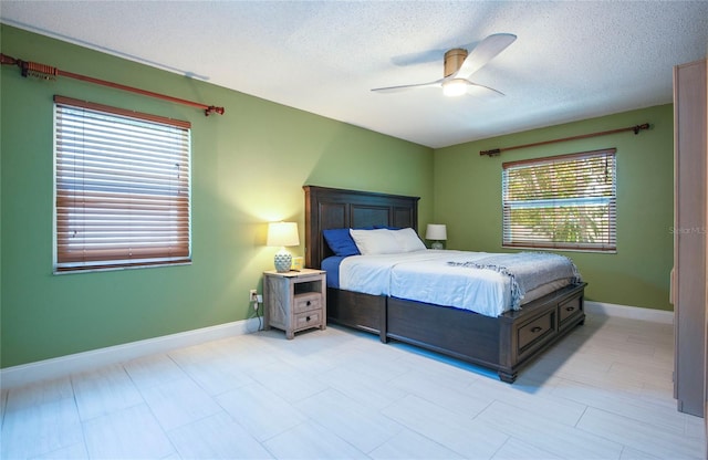 bedroom with a textured ceiling, a ceiling fan, and baseboards