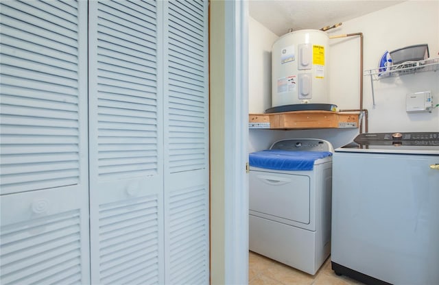 laundry area with light tile patterned floors, water heater, and washer and clothes dryer