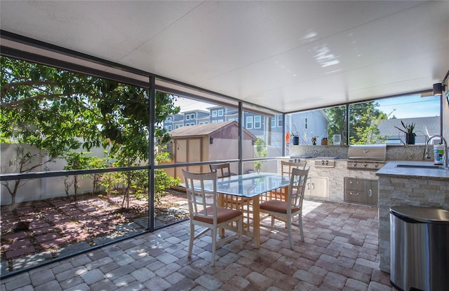 sunroom / solarium with outdoor dining area, a sink, exterior kitchen, and a healthy amount of sunlight