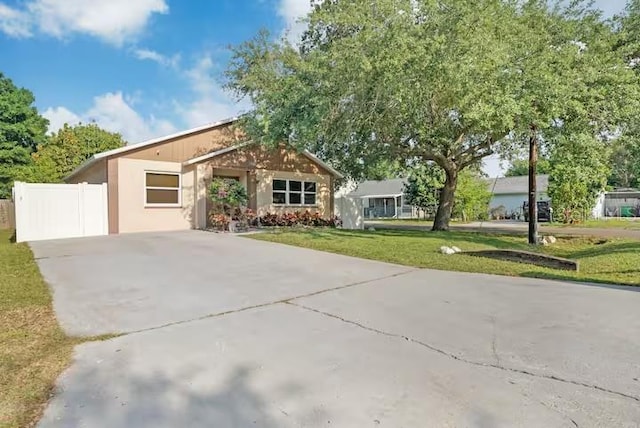 ranch-style home featuring fence, a front lawn, and concrete driveway