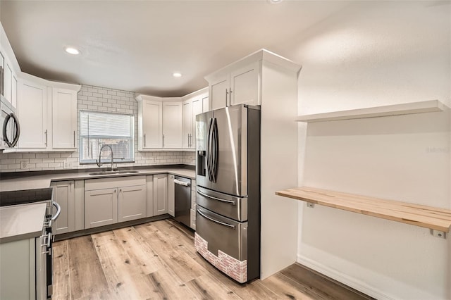 kitchen with a sink, stainless steel appliances, recessed lighting, decorative backsplash, and light wood-type flooring
