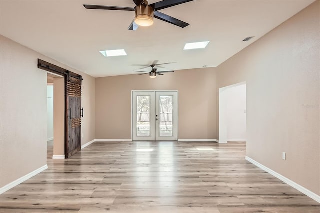 4018 Indianapolis St NE, Saint Petersburg, FL 33703 - unfurnished room with a ceiling fan, a barn door, a skylight, and light wood-style floors