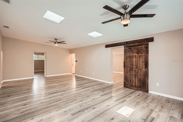 4018 Indianapolis St NE, Saint Petersburg, FL 33703 - empty room featuring ceiling fan, a skylight, a barn door, and light wood-style flooring