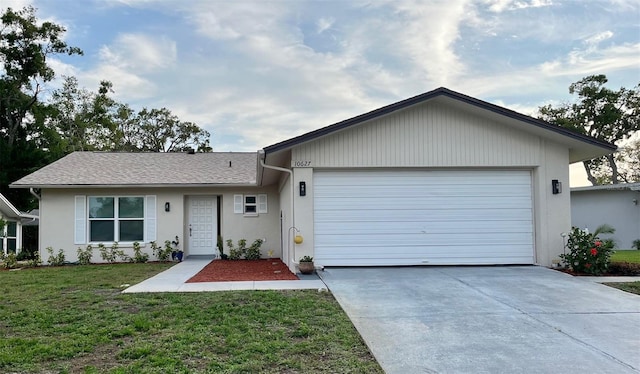 single story home featuring an attached garage, concrete driveway, stucco siding, and a front yard