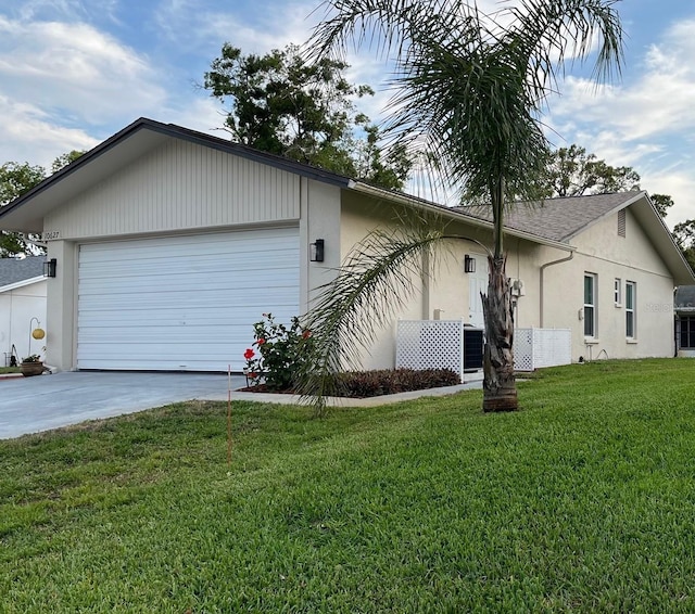 view of side of home with a garage, central AC, stucco siding, concrete driveway, and a yard