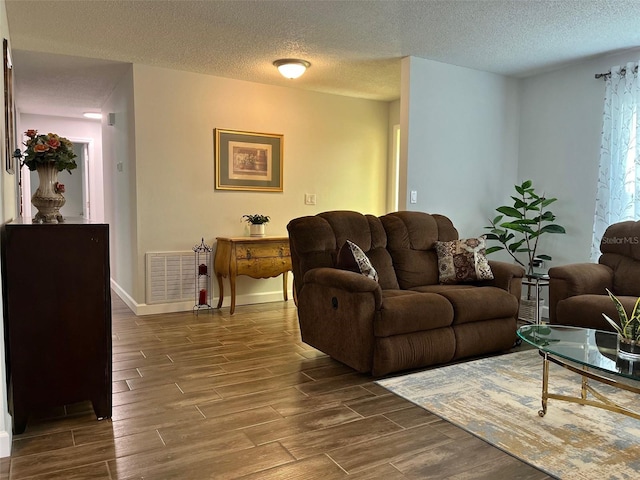 living room featuring baseboards, dark wood finished floors, visible vents, and a textured ceiling