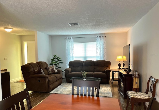 living room with a textured ceiling, visible vents, and wood finished floors