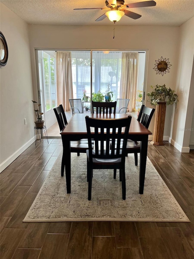dining area featuring dark wood finished floors, baseboards, ceiling fan, and a textured ceiling