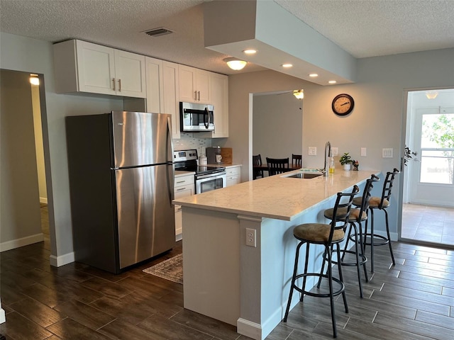 kitchen with a kitchen breakfast bar, wood tiled floor, visible vents, and appliances with stainless steel finishes