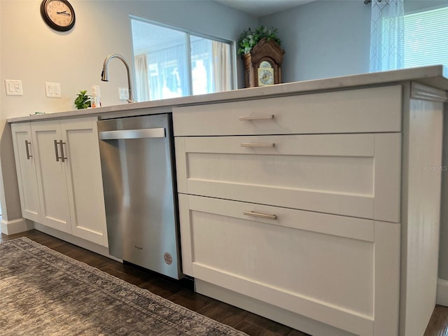 kitchen with white cabinetry, a sink, stainless steel dishwasher, and dark wood-type flooring
