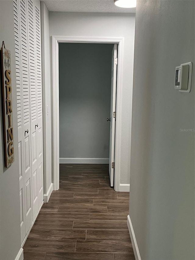 corridor with dark wood-style flooring and baseboards