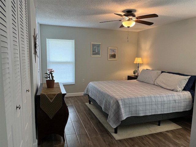 bedroom with dark wood-style flooring, a textured ceiling, baseboards, and ceiling fan