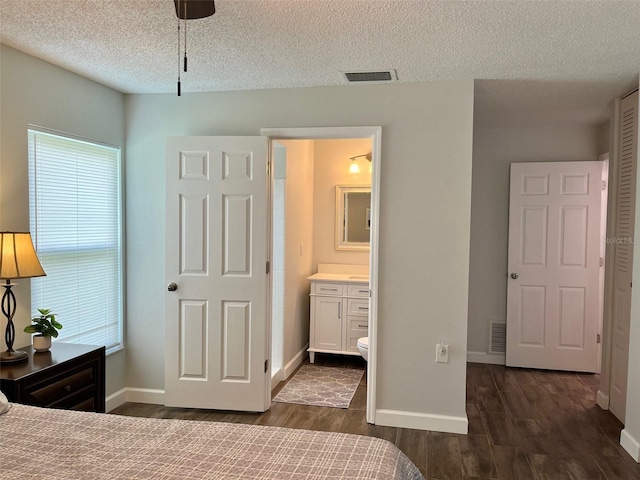 bedroom with a textured ceiling, dark wood-style floors, visible vents, and multiple windows