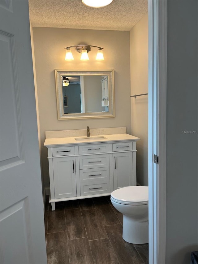 bathroom with vanity, a textured ceiling, wood tiled floor, and toilet