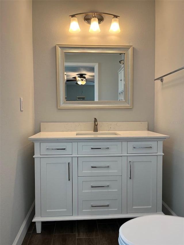 bathroom with baseboards, vanity, and toilet
