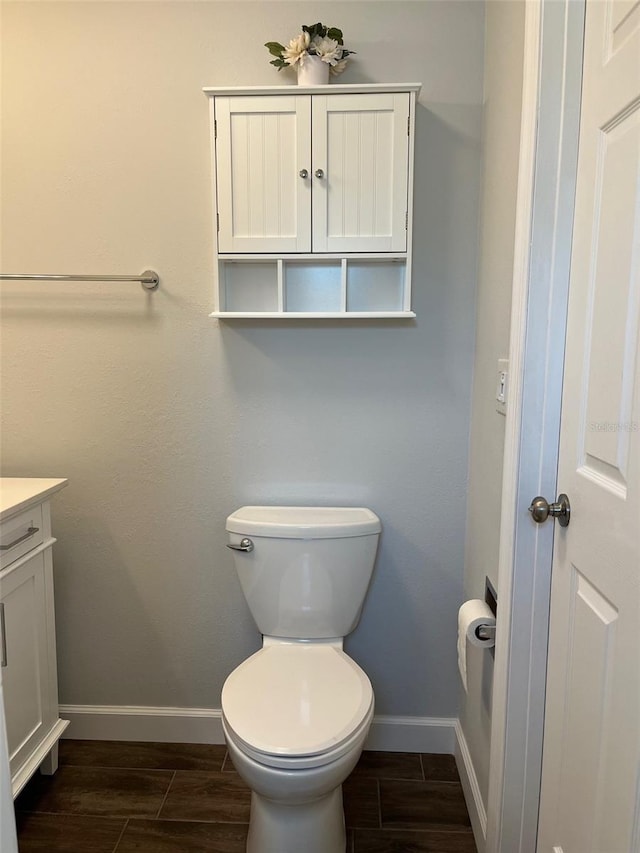 bathroom with baseboards, vanity, toilet, and wood finish floors