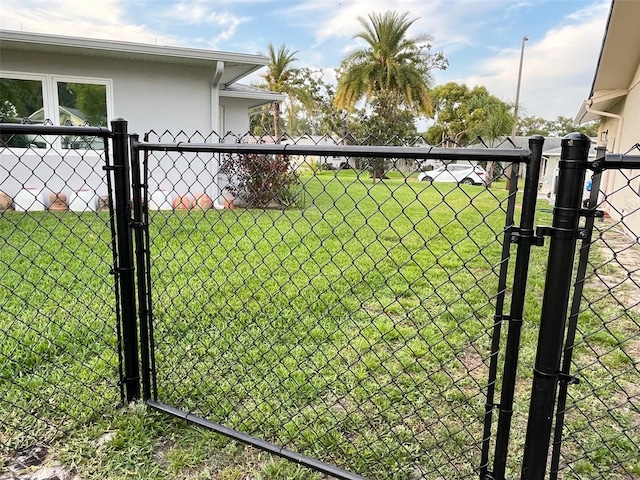 view of gate with fence and a lawn