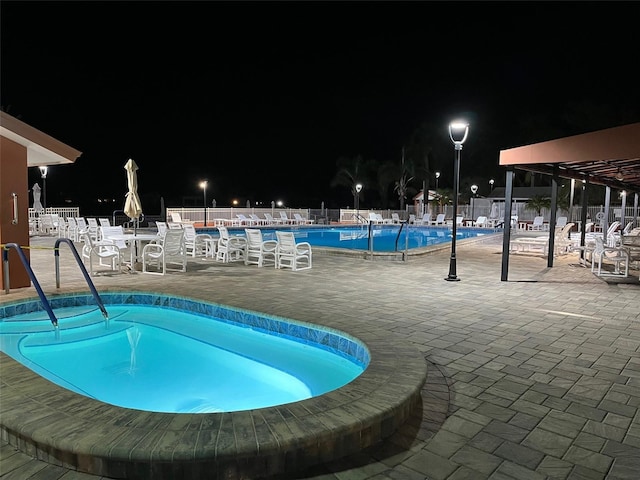 pool at twilight with a community pool, fence, and a patio area