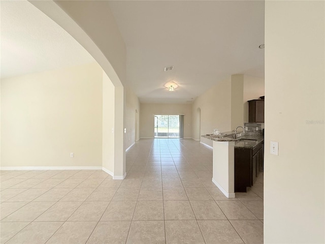 13181 Royal Pines Ave, Riverview, FL 33579 - kitchen featuring open floor plan, light tile patterned floors, arched walkways, a sink, and stone countertops