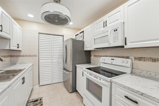 1515 12th Ct SE Unit 55, Largo, FL 33771 - kitchen featuring white appliances, a sink, light tile patterned floors, white cabinetry, and backsplash
