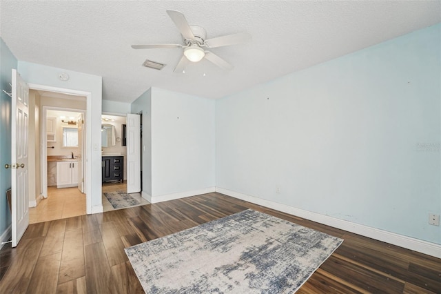 1515 12th Ct SE Unit 55, Largo, FL 33771 - unfurnished bedroom with wood finished floors, baseboards, ensuite bath, ceiling fan, and a textured ceiling