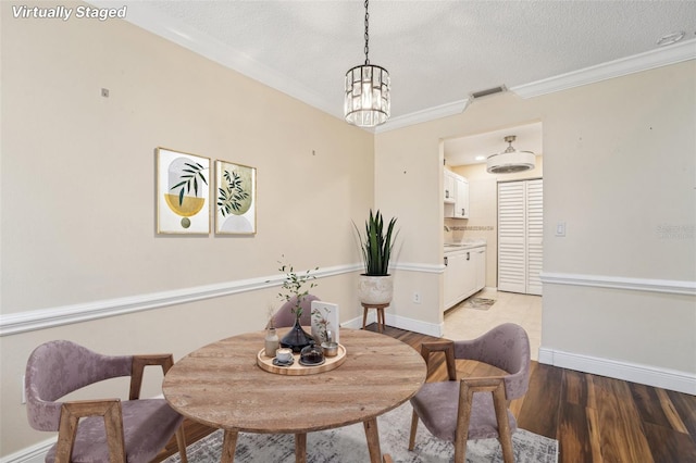 1515 12th Ct SE Unit 55, Largo, FL 33771 - dining area with a textured ceiling, a chandelier, light wood-type flooring, crown molding, and baseboards