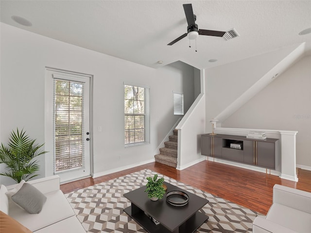 living room featuring ceiling fan, visible vents, wood finished floors, and stairway