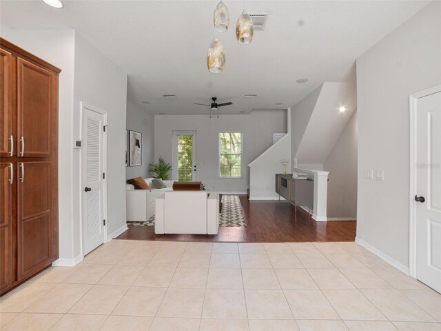interior space featuring light tile patterned floors, baseboards, a ceiling fan, and visible vents