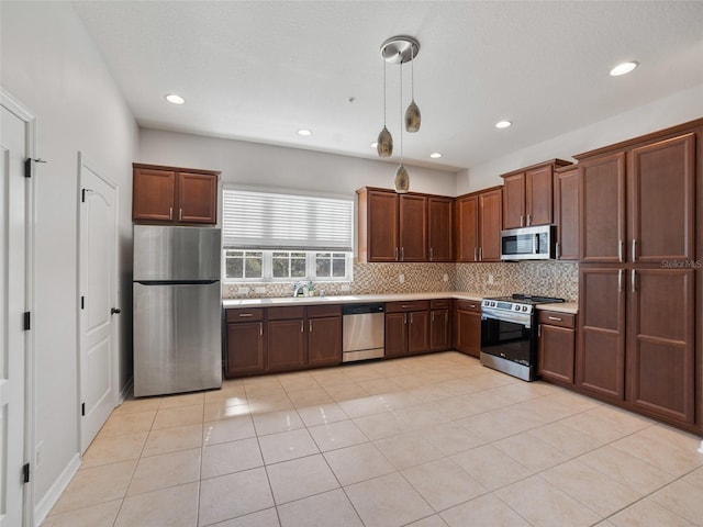 kitchen with a sink, light countertops, stainless steel appliances, decorative light fixtures, and decorative backsplash