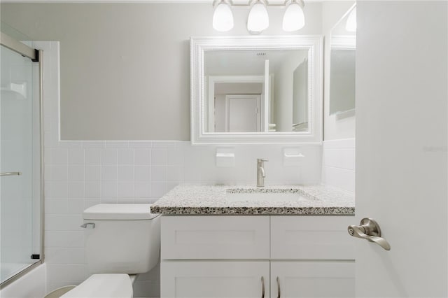 2457 Ecuadorian Way Unit 63, Clearwater, FL 33763 - bathroom with tile walls, wainscoting, vanity, combined bath / shower with glass door, and toilet