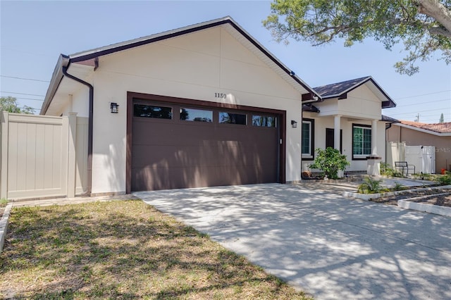 view of front of property featuring fence, stucco siding, concrete driveway, and an attached garage