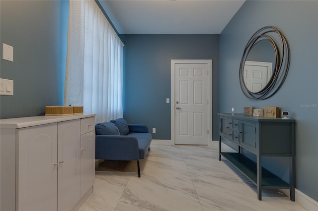 living area featuring baseboards and marble finish floor