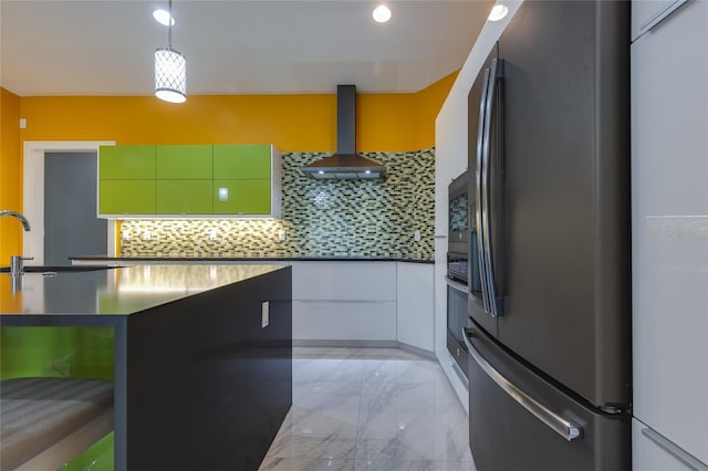 kitchen featuring decorative backsplash, freestanding refrigerator, wall chimney range hood, marble finish floor, and modern cabinets