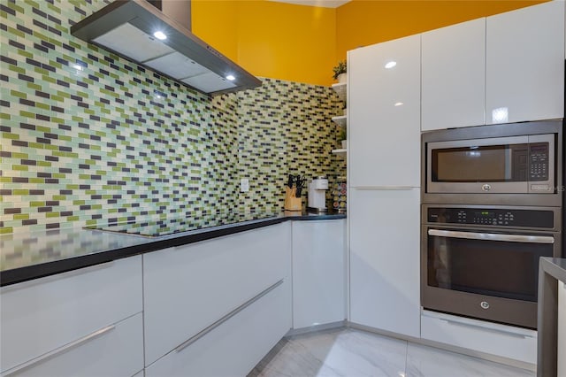 kitchen with dark countertops, white cabinetry, stainless steel appliances, and custom range hood