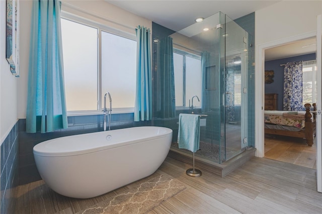 bathroom featuring a stall shower, tile walls, a freestanding tub, and connected bathroom