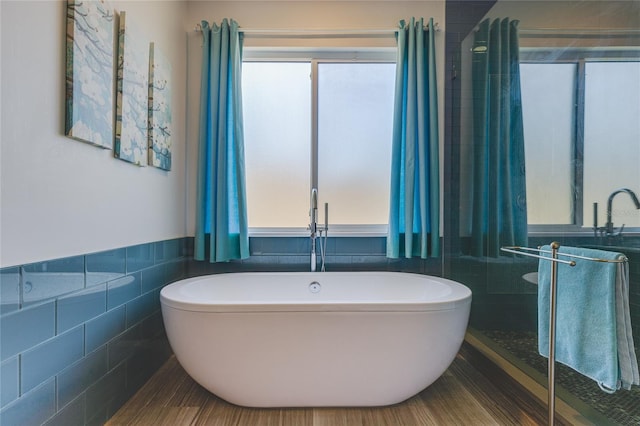 bathroom featuring tile walls, a freestanding bath, and a wainscoted wall