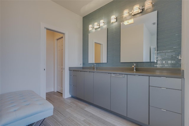 full bathroom featuring double vanity, a sink, backsplash, and baseboards