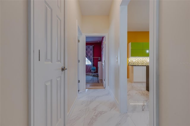 hall with baseboards, arched walkways, and marble finish floor