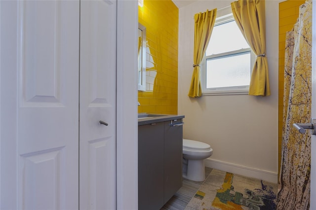 bathroom with toilet, vanity, and baseboards