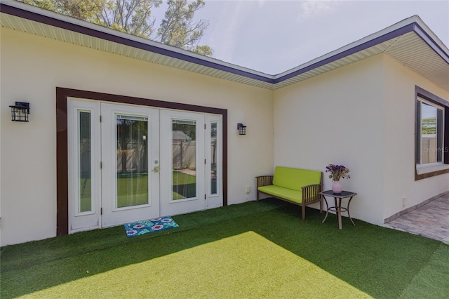 back of house featuring stucco siding, a lawn, and french doors