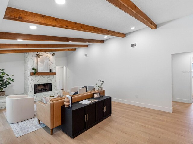 living room featuring a stone fireplace, recessed lighting, light wood-style flooring, and visible vents