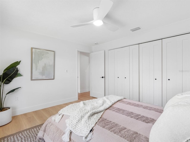 bedroom featuring visible vents, a closet, baseboards, ceiling fan, and light wood finished floors