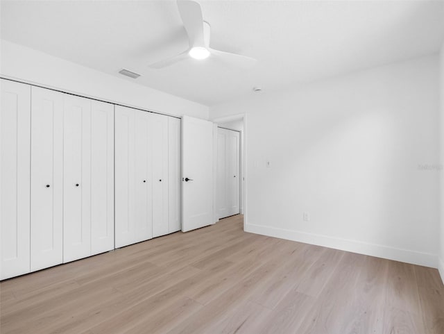unfurnished bedroom featuring light wood-style floors, baseboards, visible vents, and a closet