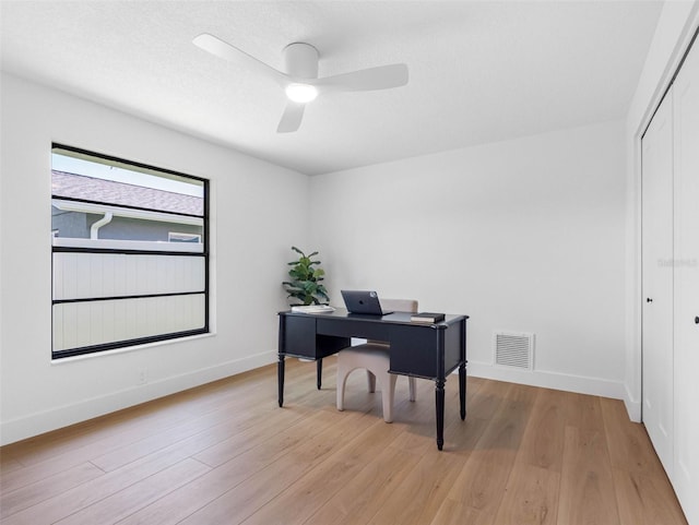 office space featuring baseboards, a ceiling fan, light wood finished floors, and visible vents