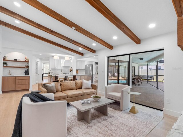 living room with light wood finished floors, baseboards, lofted ceiling with beams, and recessed lighting